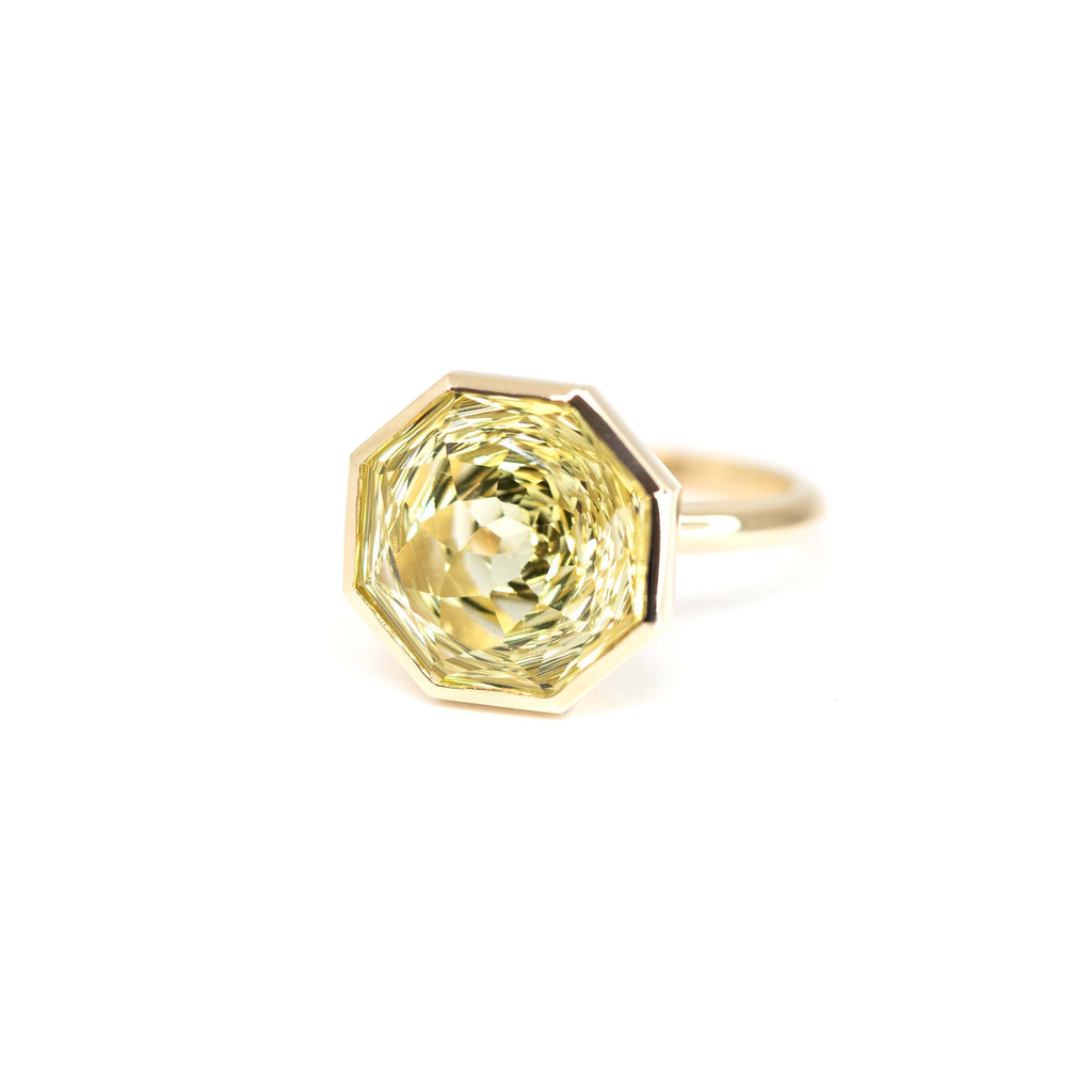 Side view of a big statement ring featuring a bright light green gem (lemon quartz) set in yellow gold that was custom made in montreal by local brand Bena Jewelry.