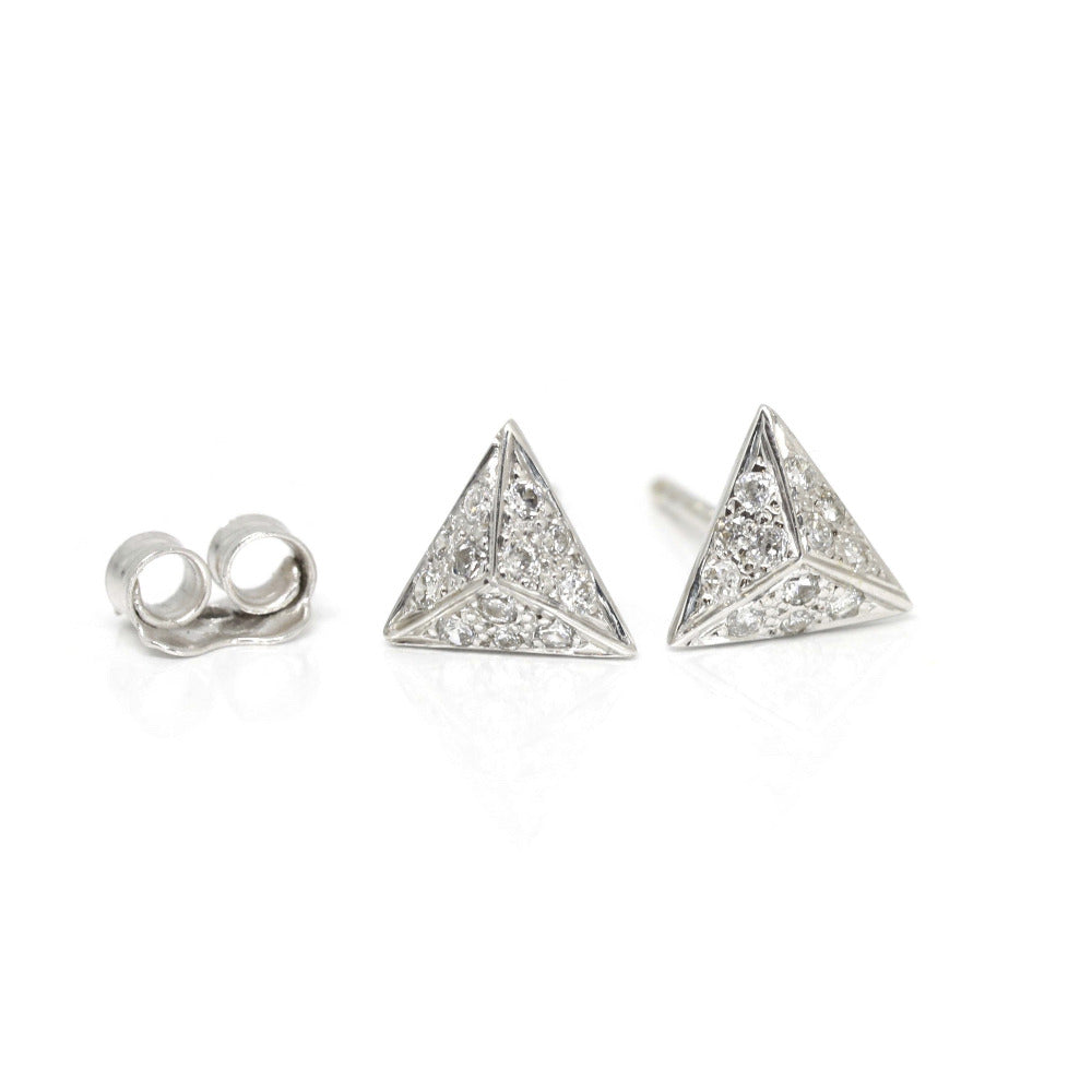 Small pyramid-shaped stud earrings in white gold with pave-set diamonds by Bena Jewelry. Edgy and modern fine jewelry, crafted in Montreal by an independent Canadian designer. Displayed against a white background with butterfly earring backs beside them.