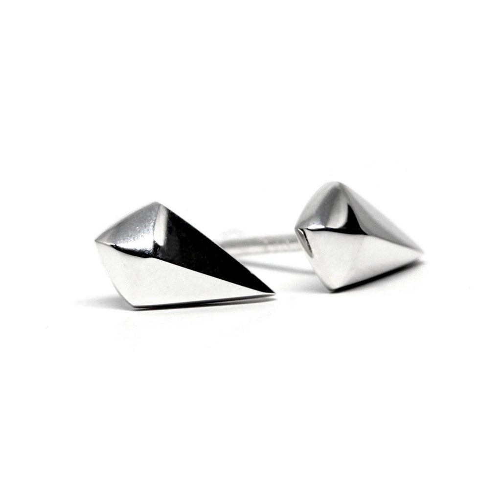 Flatlay of asymmetric white gold stud earrings with mixed metals, highlighting clean lines and bold edges on white.